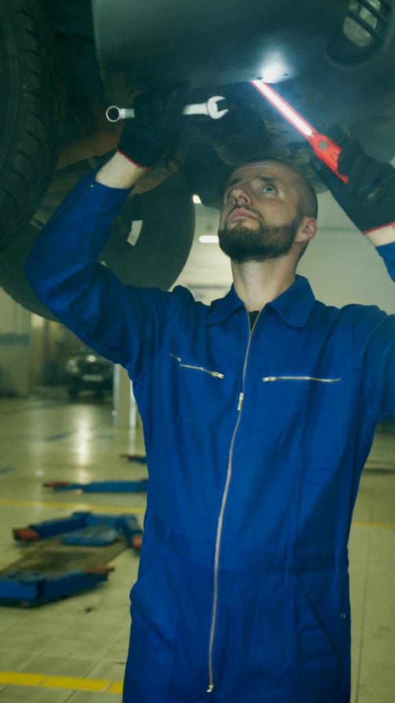 Mechanic inspecting a vehicle under a lift